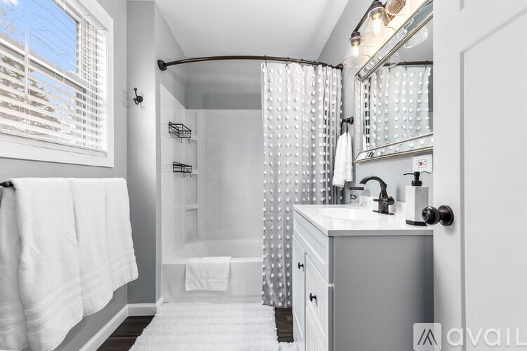 A white bathroom with a shower curtain and a white towel hanging on the wall.