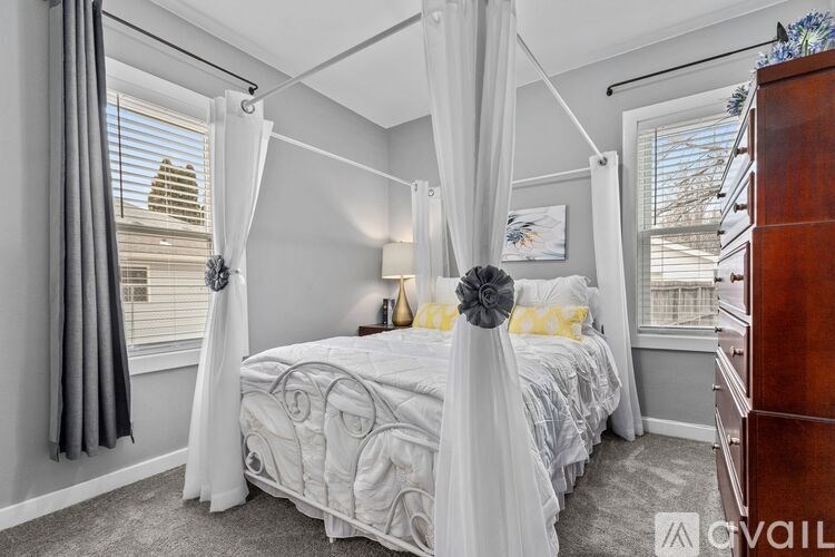 A bedroom with a canopy bed and a window with blinds.