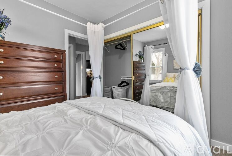 A bedroom with a large bed and a wooden dresser.