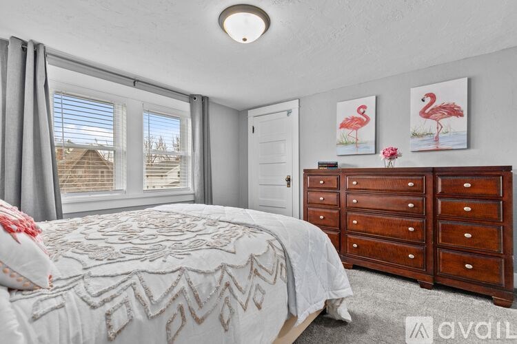 A bedroom with a bed, dresser, and two framed pictures of flamingos.