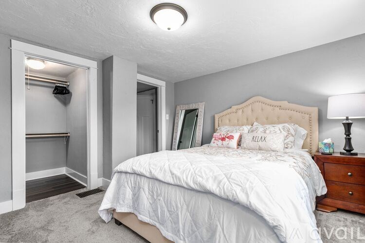 A bedroom with a large bed and a lamp on the nightstand.