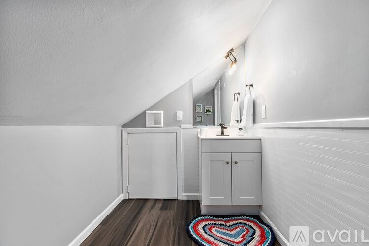 A bathroom with a white cabinet and a heart-shaped rug on the floor.