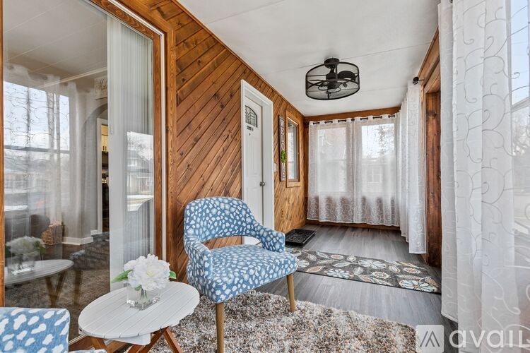 A blue and white patterned chair sits in a room with wooden walls and a white ceiling.