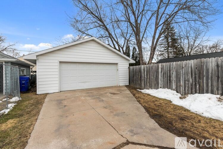 A detached house with a white garage door and a wooden fence.