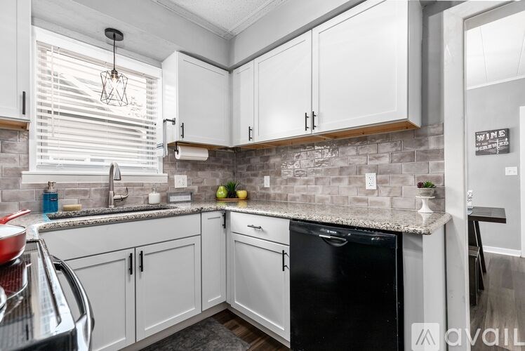 A kitchen with white cabinets and a black dishwasher.
