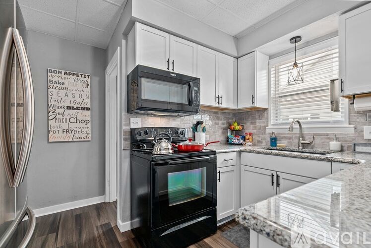 A black oven sits in a kitchen with white cabinets and a white fridge.