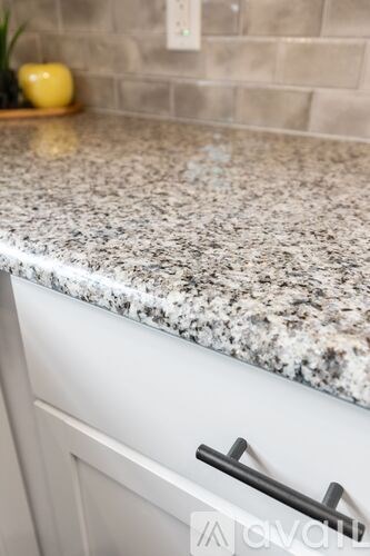A kitchen counter with a granite surface and a white drawer with a black handle.