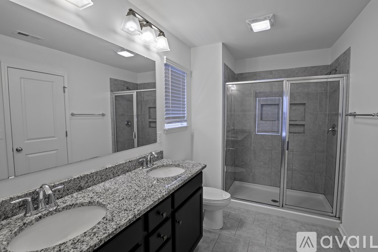 A bathroom with a granite countertop and a walk-in shower.