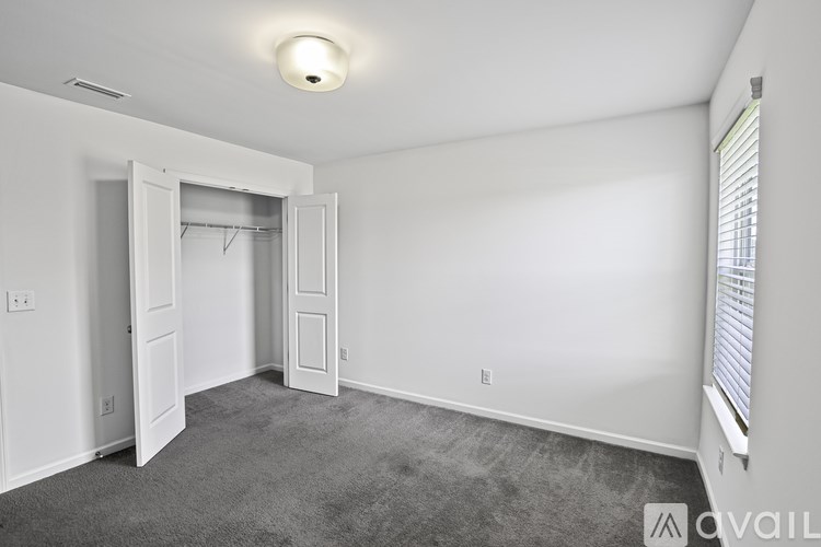 A room with a carpeted floor and a window with blinds.