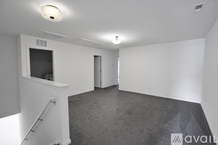 A spacious room with a carpeted floor and white walls.