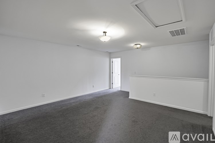 A spacious room with a carpeted floor and white walls.