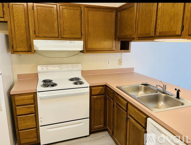 A kitchen with wooden cabinets and a white stove top oven.