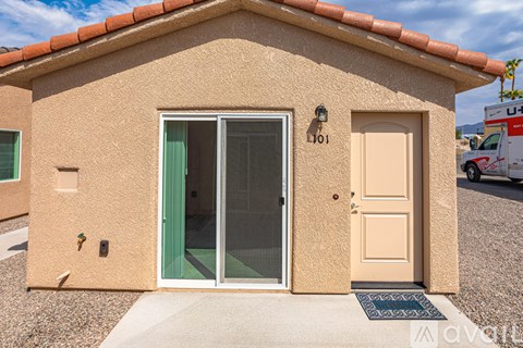 A small house with a brown door and a brown mat in front of it.