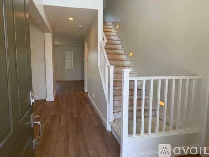A hallway with a staircase and a door on the left.