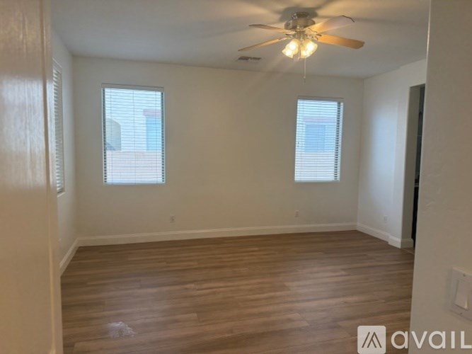 A room with a ceiling fan and two windows.