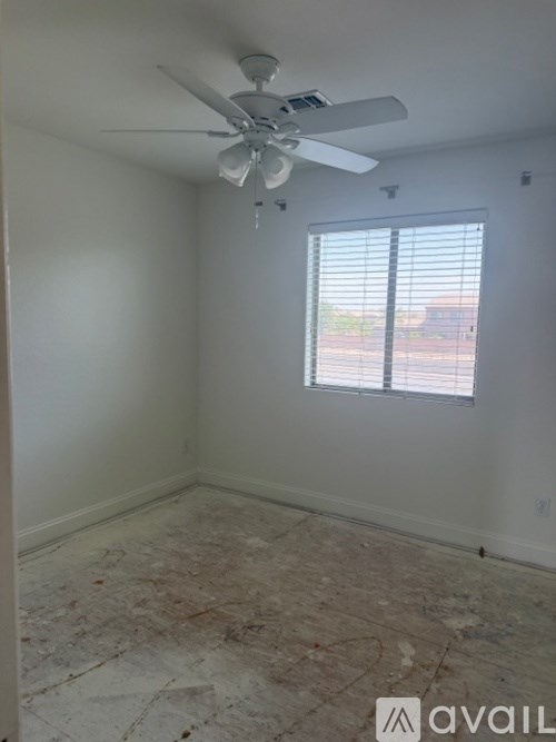 A room with a ceiling fan and a window with blinds.