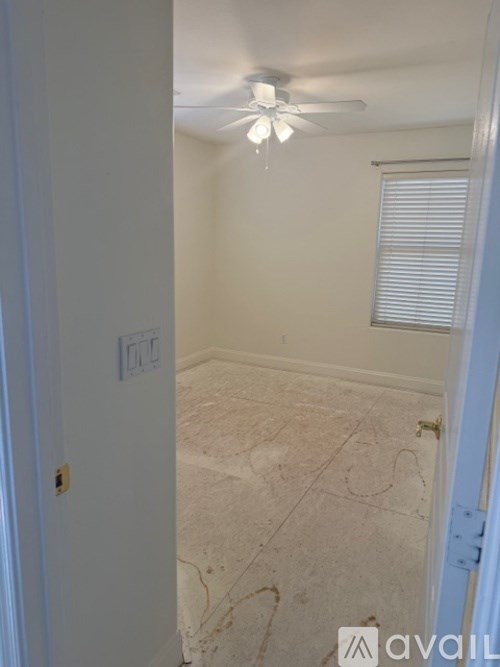 A room with a ceiling fan and a door with a handle.