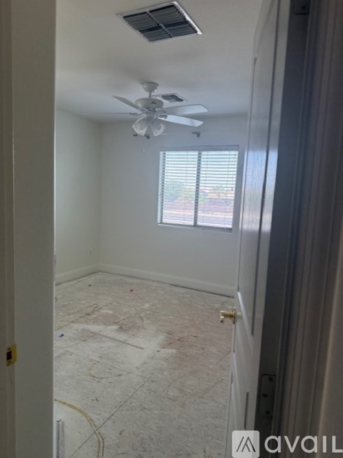 A room with a ceiling fan and a window with blinds.