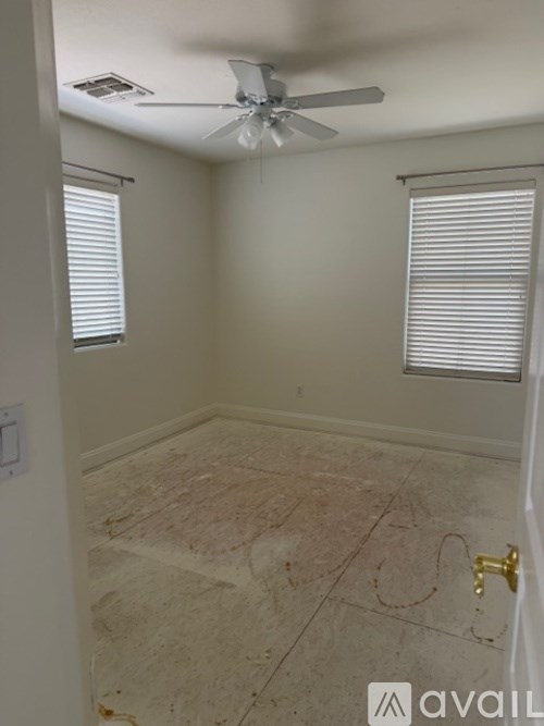A room with a ceiling fan and a window with blinds.