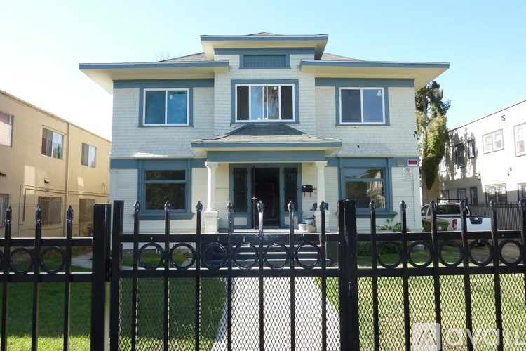 A two-story house with a black fence in front.