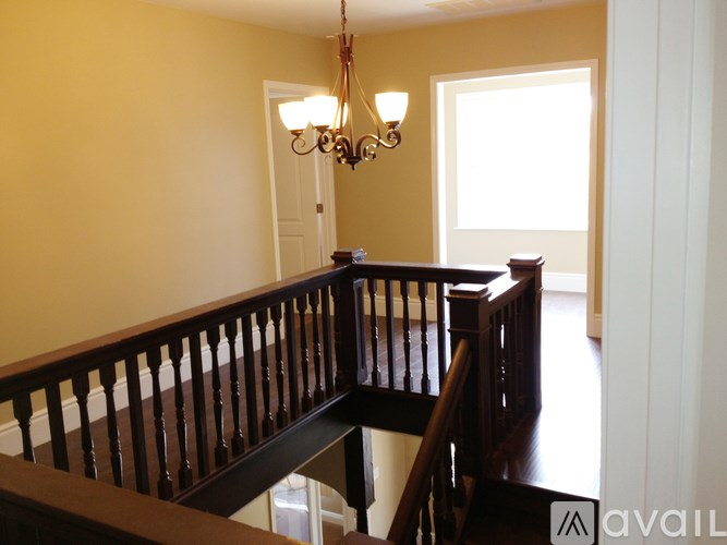 A chandelier hangs over a staircase with a wooden balustrade.