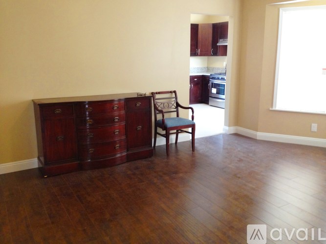 A brown wooden dresser with a chair in front of it in a room.