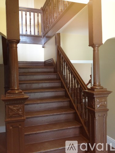 A wooden staircase with a balustrade and a logo in the bottom right corner.