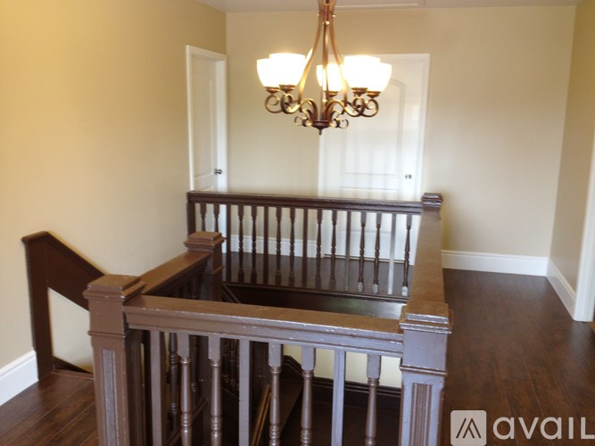 A chandelier hangs over a staircase with a wooden banister.