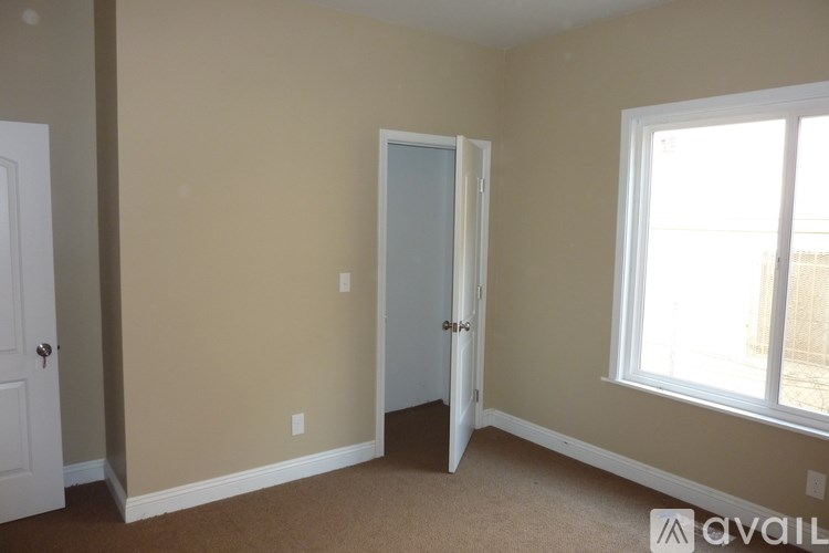 A room with beige walls and carpeted floor with a door open to another room.
