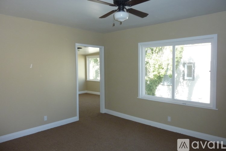 A room with a ceiling fan and a window with a view of trees.