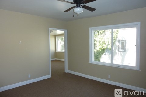 A room with a ceiling fan and a window with a view of trees.
