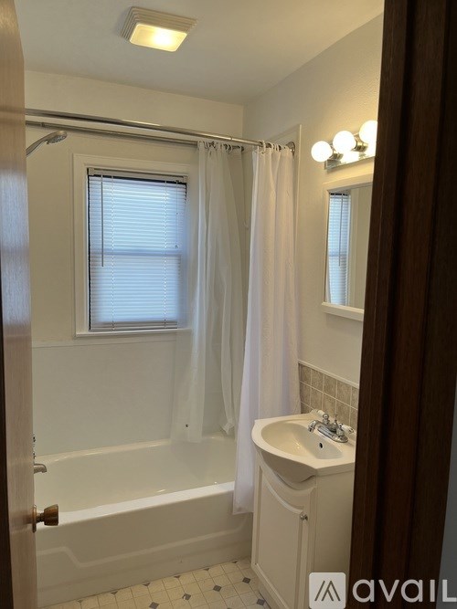 A white bathroom with a tub, sink and shower.