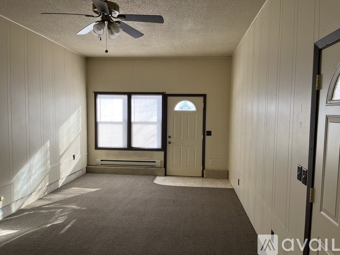 A room with a ceiling fan and a door leading to another room.