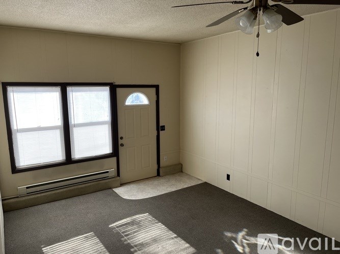 A room with a ceiling fan and a carpeted floor.