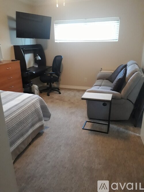 A bedroom with a bed, a chair, a desk, and a couch.