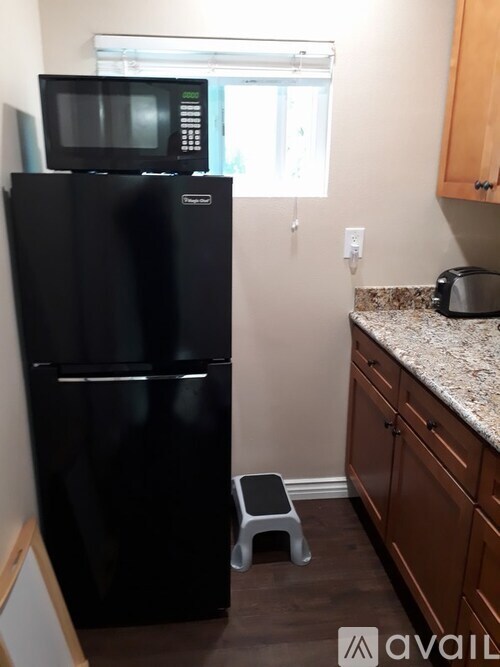 A black fridge in a kitchen with a microwave on top.
