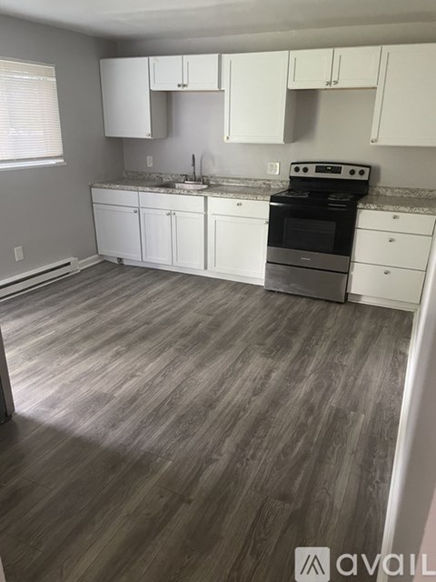 A kitchen with white cabinets and a wooden floor.
