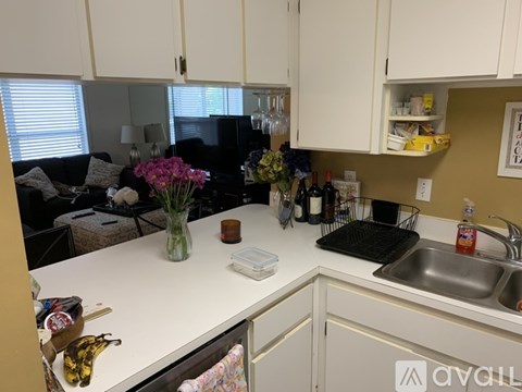 A kitchen with white cabinets and a black refrigerator.