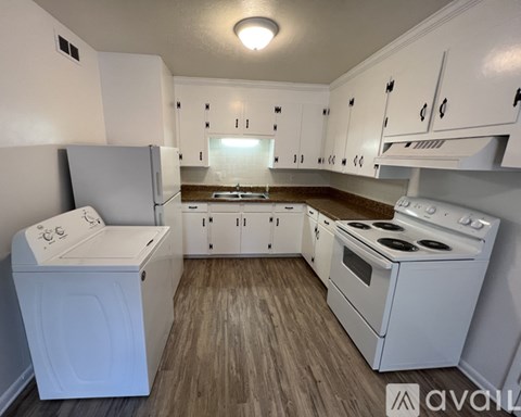 A small, clean, and well-organized kitchen with white appliances and cabinets.