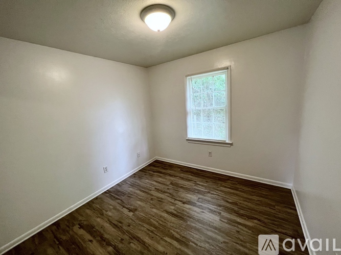 A room with a window and wooden flooring is available for rent.
