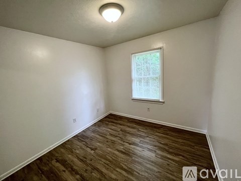 A room with a window and wooden flooring is available for rent.
