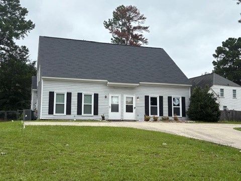 A grey house with a black roof and white trim.