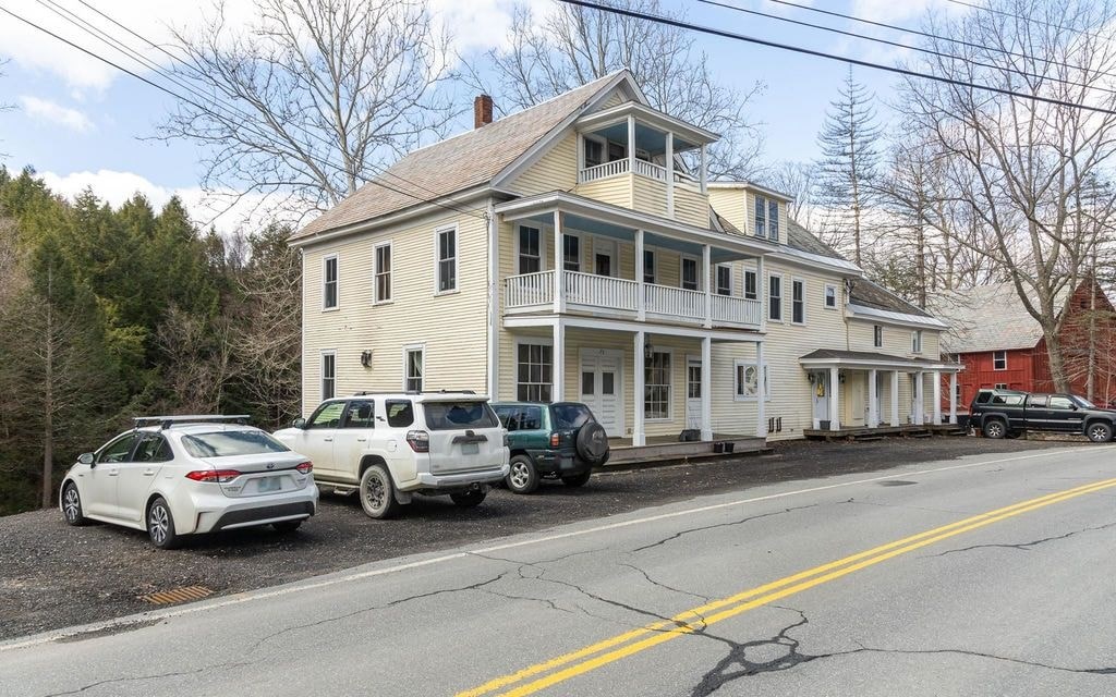 A white house with a car parked in front.
