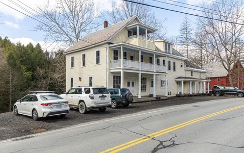 A white house with a car parked in front.
