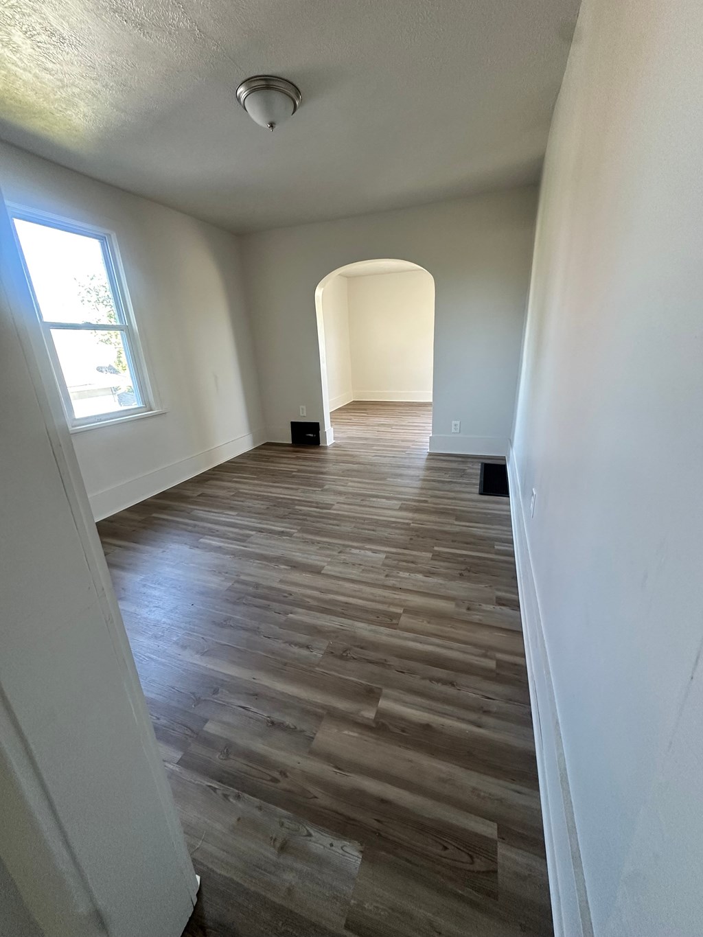 A room with wooden flooring and white walls.