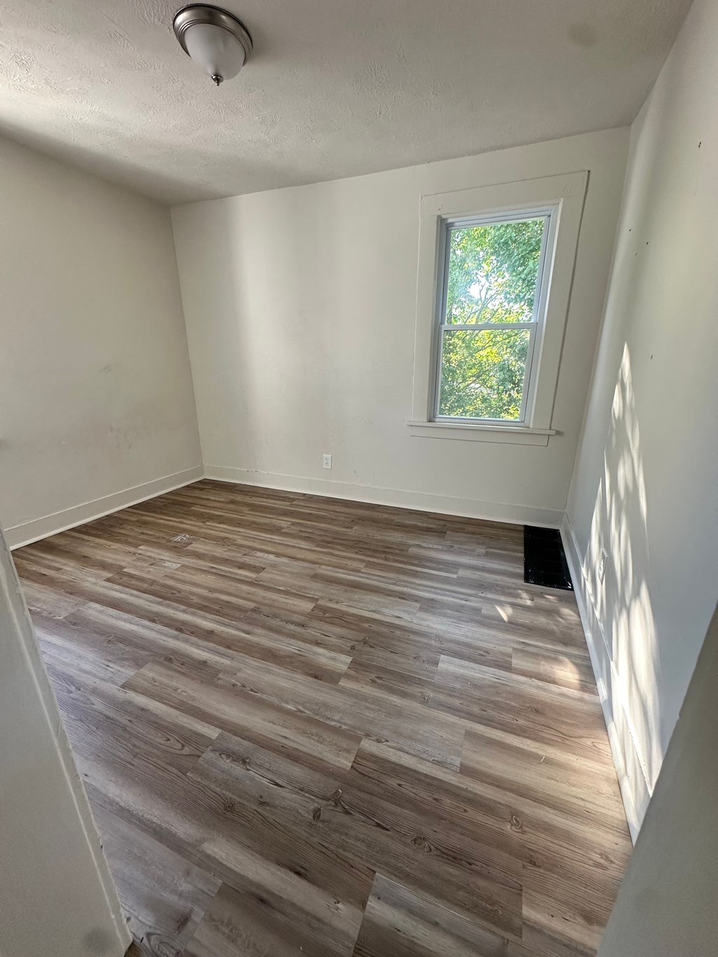 A room with a window and wooden flooring.