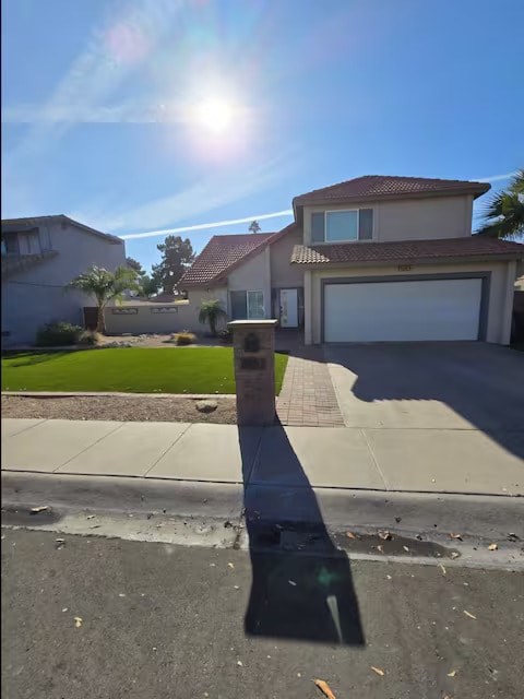 A house with a garage is reflected in a puddle on the street.