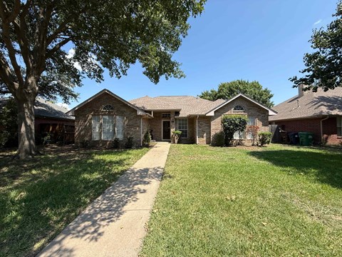 A house with a brown roof and a green lawn in front.