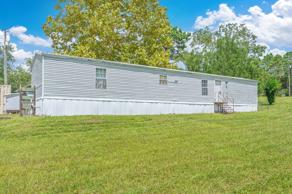 A large silver building with a green lawn in front.