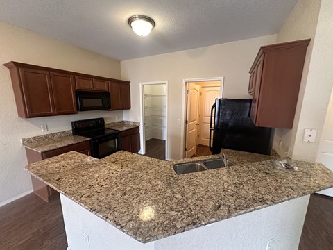 A kitchen with granite countertops and wooden cabinets.